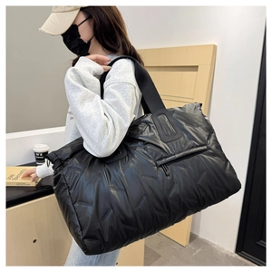 Detail of black quilted puffer tote bag showing water-resistant texture and front zipper