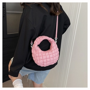 Detail of pink quilted nylon crossbody bag with textured grid stitching on a model