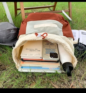 Outdoor camping scene showing a color-block drawstring backpack with large storage capacity