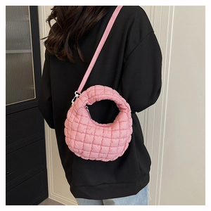 Detailed shot of pink quilted nylon crossbody bag with adjustable strap and zip closure