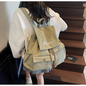 Detailed view of light olive green canvas backpack with drawstring and flap on model
