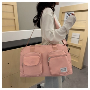 Model wearing a pink nylon travel bag with large front pockets and adjustable strap
