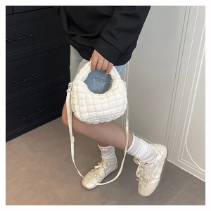 White quilted moon-shaped bag with puff detail shown being worn in lifestyle setting