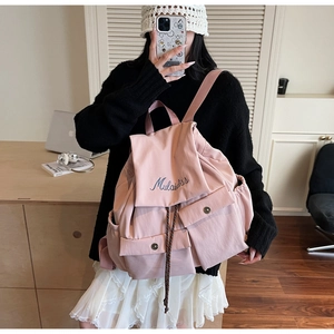 Detail view of pink canvas backpack with Mulaidiss embroidery and magnetic buckle pockets