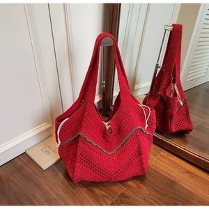 Detail of red hand-knit tote bag with green wavy trim and white drawstring closure