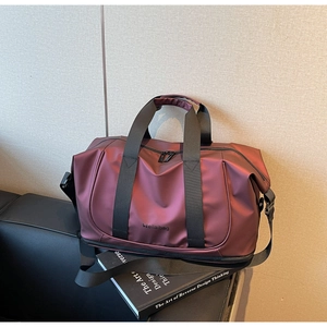Close-up of burgundy travel bag showing reinforced handles and detachable shoulder strap