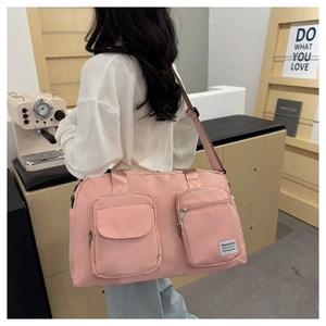 Detail view of pink waterproof nylon travel bag with functional pockets and wide strap