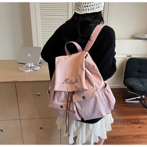 Detail of pink nylon backpack featuring Mulaidss embroidery and functional front pockets