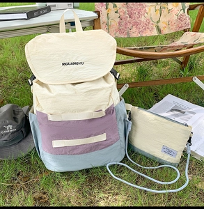 Detail view of canvas backpack and crossbody bag set in ivory and lilac color blocking