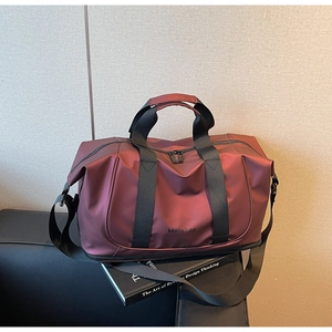 Close-up of burgundy waterproof travel bag with bottom compartment on a leather sofa
