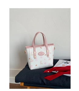 Close-up of printed white bucket bag with pink handles and cute cartoon rabbit patterns