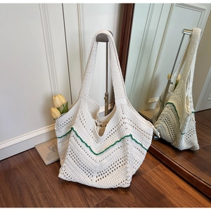 Detail of white crochet tote bag with green wavy lines and inner drawstring pouch