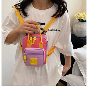 Detail of multi-color crossbody bag with pink, purple and yellow contrast panels and logo