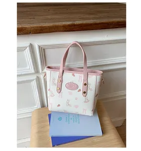 Detail of a white leather bucket bag with pink rabbit prints and metallic rivets on wood