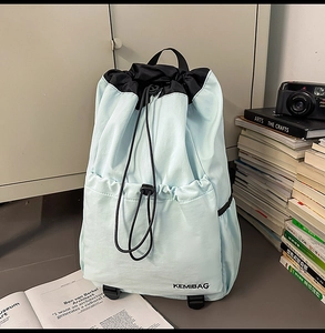Detail of mint green nylon backpack showing waterproof texture and black drawstring closure