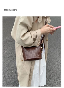 Outdoor model show featuring a brown woven bucket bag with beaded tassel and beige trench coat