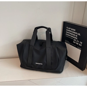 Detail of waterproof matte black travel bag with dual handles and logo on marble surface