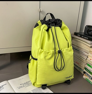 Detail of neon yellow nylon backpack with drawstring closure and KEMIBAG logo print