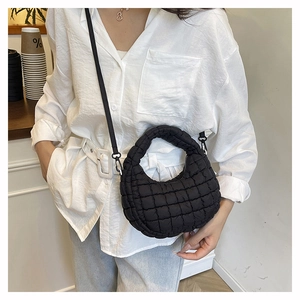 Model wearing a black quilted cloud crossbody bag with soft puffer texture and strap