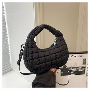 Detail of black quilted puffer handbag featuring puffy texture and silver metal zipper