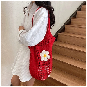 Détail d'un sac cabas en crochet rouge avec marguerite blanche et texture en maille