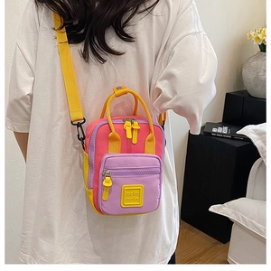 Detail of multi-color crossbody bag with pink and purple panels and adjustable strap