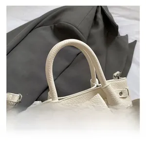 Dettaglio di una borsa in pelle litchi bianco crema con elegante fiocco decorativo
