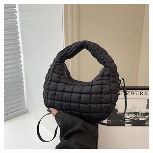 Detail of black puffer dumpling bag showing quilted nylon texture and removable strap