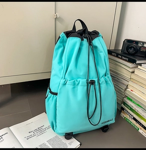 Close-up of green nylon backpack showing KEMIBAG logo and drawstring closure detail