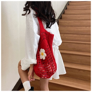 Détail du sac cabas rouge crocheté à la main avec une application de marguerite blanche