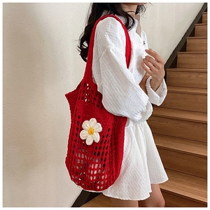 Détail d'un sac cabas en crochet rouge avec fleur de marguerite et maille ajourée
