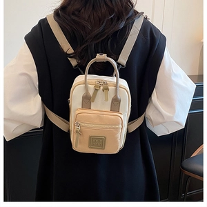 Detailed back view of a mini beige and khaki crossbody backpack worn by a model