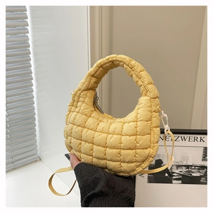 Macro detail of vibrant yellow quilted cloud bag with textured bubble fabric and soft handle
