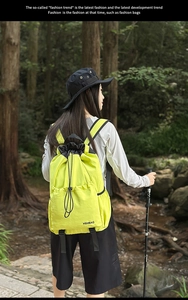 Detail of neon green drawstring nylon backpack showing multiple storage pockets outdoors