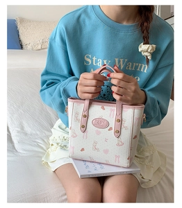 Close-up of pink bunny pattern on white mini tote bag with gold metal hardware details