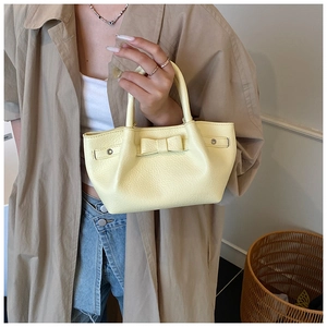 Dettaglio della mini borsa tote gialla con trama in pelle martellata e fiocco
