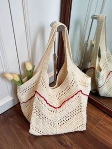 Minimalist beige woven tote bag with red scalloped trim hanging in home setting