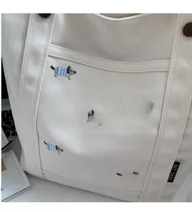 Gros plan d'un sac cabas en toile crème avec broderie de chien bleu et étiquette de marque