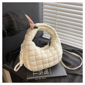 Detail of white quilted puffy handbag with adjustable strap on a stylish black background