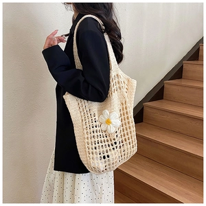 Gros plan du sac fourre-tout tressé crème orné de marguerites tricotées blanches