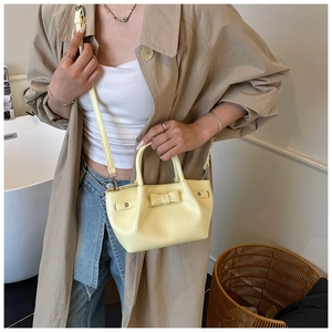 Dettaglio di una borsa a secchiello in pelle giallo tenue con fiocco decorativo