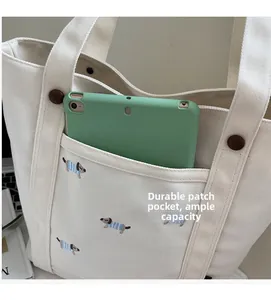 Détail de la poche avant durable du sac en toile contenant une tablette et broderie chien
