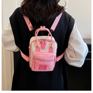 Rear view of a mini pink canvas backpack with adjustable straps worn by a model