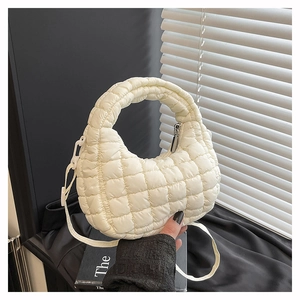 Detail of cream quilted cloud bag with top handle and shoulder strap in lifestyle setting