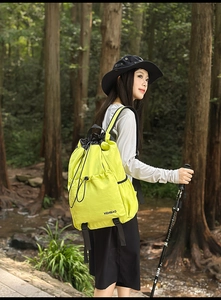 Detail view of bright yellow waterproof nylon backpack with drawstring closure in the woods