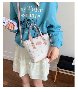 Detail of printed crossbody bucket bag with cartoon rabbit patterns and pink leather handles