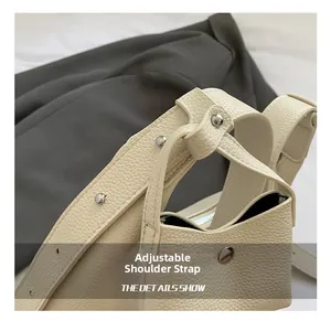 Detail of adjustable shoulder strap with silver rivets on beige pebbled leather baguette bag