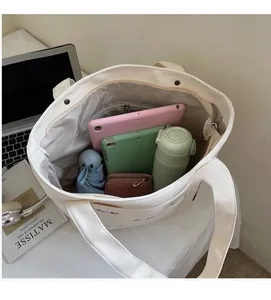 Vue intérieure du cabas en toile blanc cassé montrant la grande capacité pour tablettes