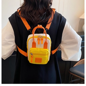 Rear view of model wearing a compact tri-color nylon mini backpack with orange straps