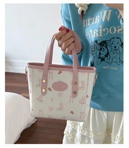 Detail of cream bucket bag with pink cartoon bunny prints and textured PU leather handle